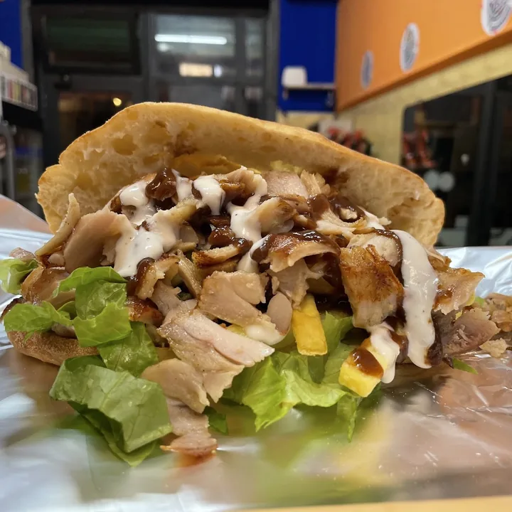 Panino kebab farcito con carne, lattuga, patatine e salsa bianca e barbecue.