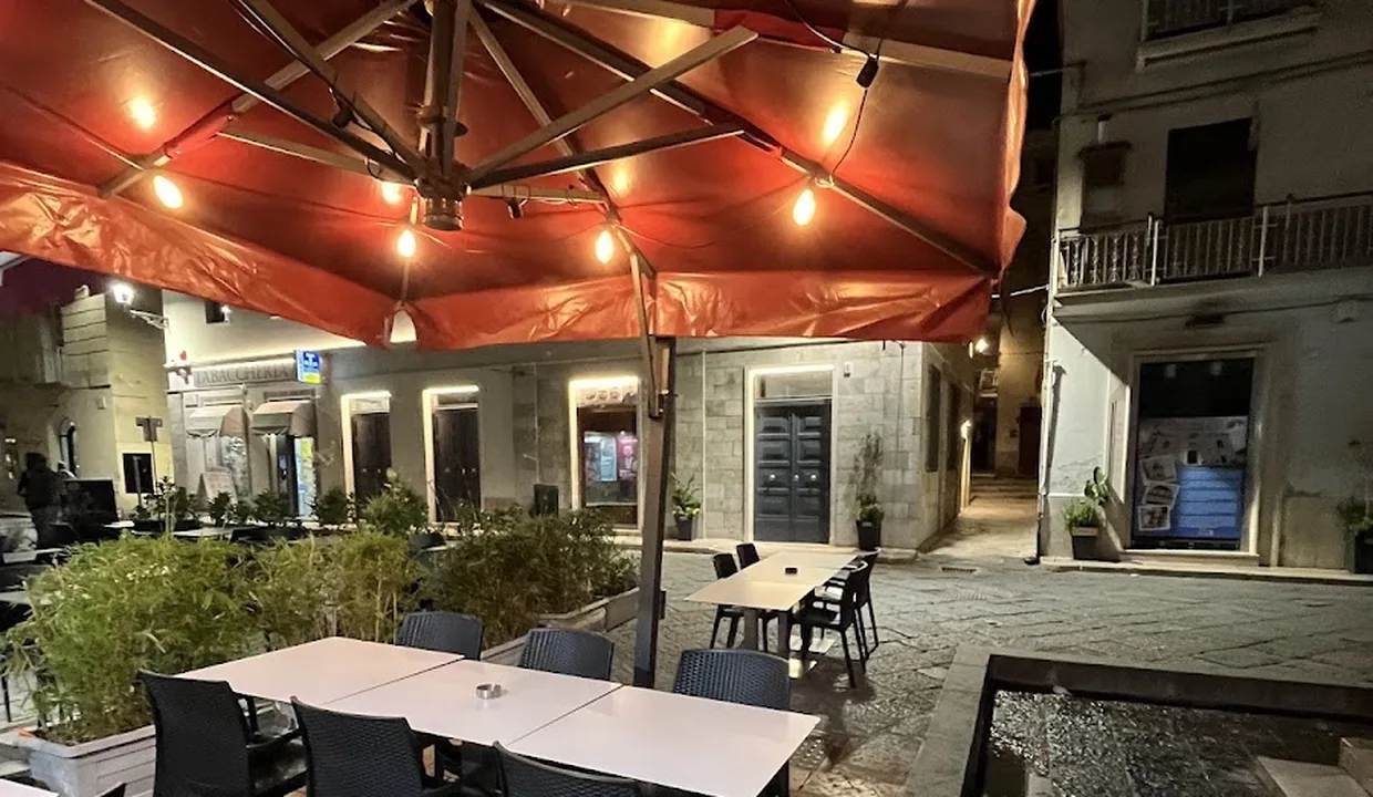 I tavolini sotto l'ombrellone con le lampadine accese, la sera, sul selciato di Piazza della Repubblica.